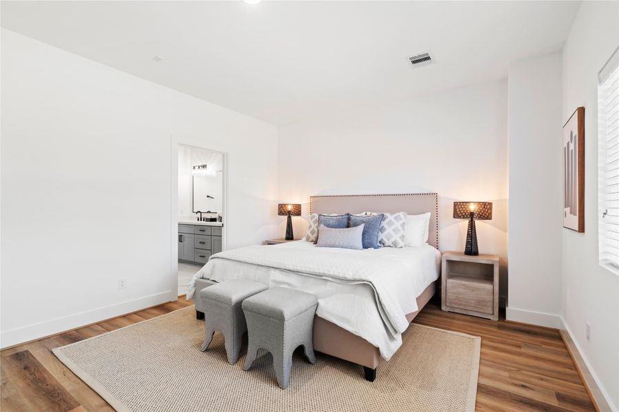 Step into your luxurious primary suite, where high ceilings, expansive windows, and premium flooring create a bright and inviting retreat. This thoughtfully designed space offers both comfort and style, perfect for unwinding at the end of the day.