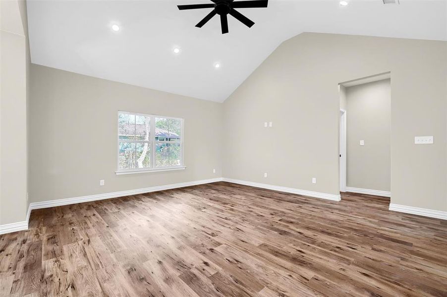 Unfurnished living room with wood-type flooring, vaulted ceiling, and ceiling fan