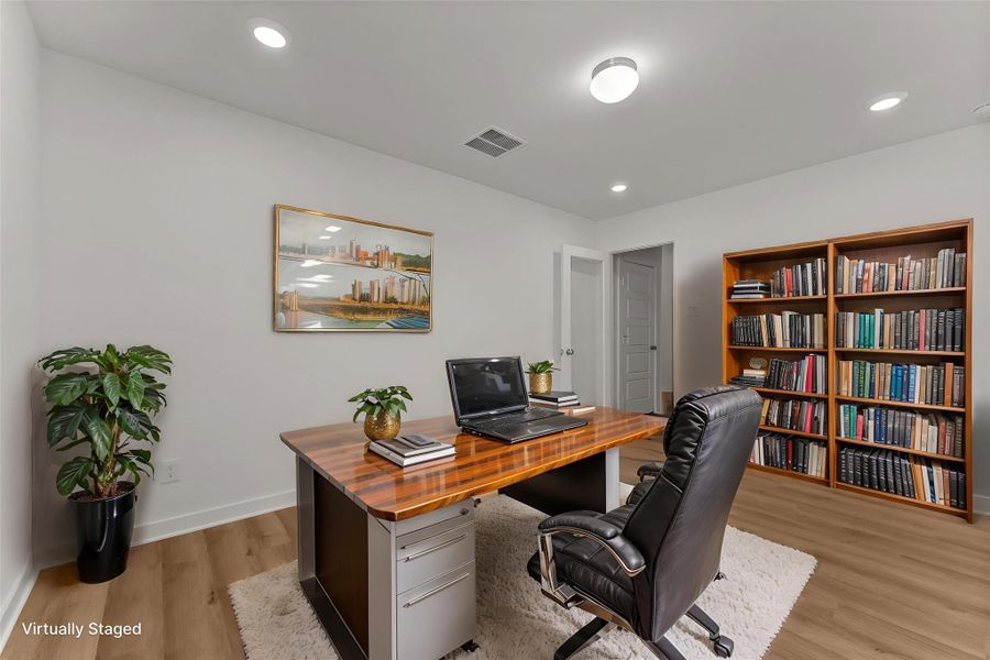 A dedicated office space features rich wood flooring and practical recessed lighting.