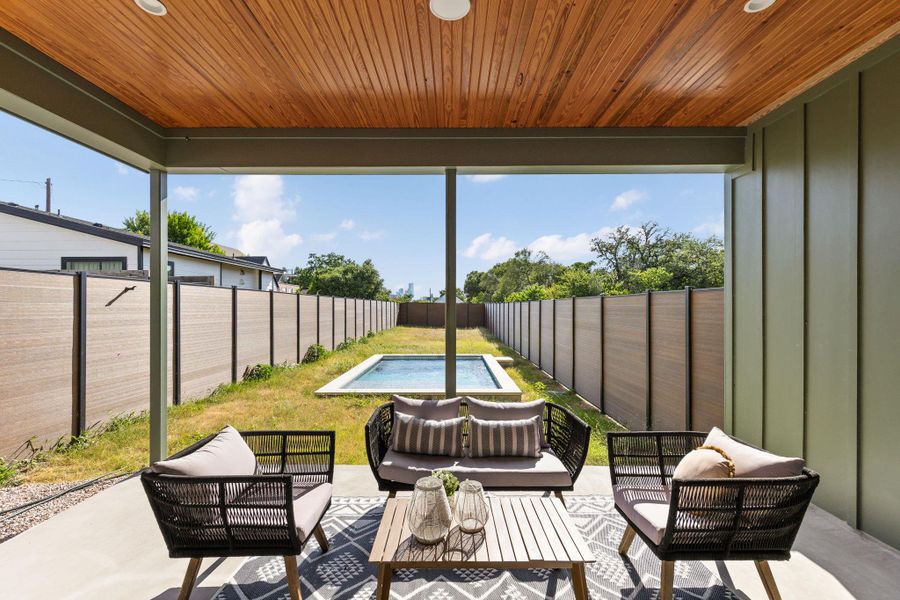 An inviting covered patio offers a refreshing pool and ample privacy, perfect for outdoor relaxation.