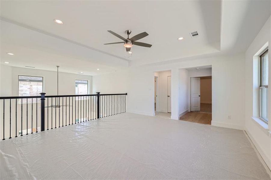 Spare room with a tray ceiling, light hardwood / wood-style flooring, and ceiling fan