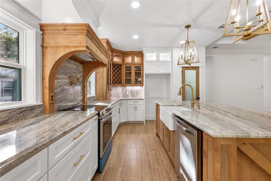 Kitchen featuring glass insert cabinets, brown cabinetry, stainless steel appliances, light stone countertops, and recessed lighting