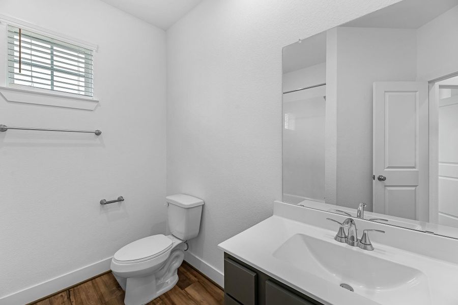 The secondary bath features tile flooring, dark stained cabinetry and light countertops and a shower/tub combo. Perfect for accommodating any visiting family and friends.