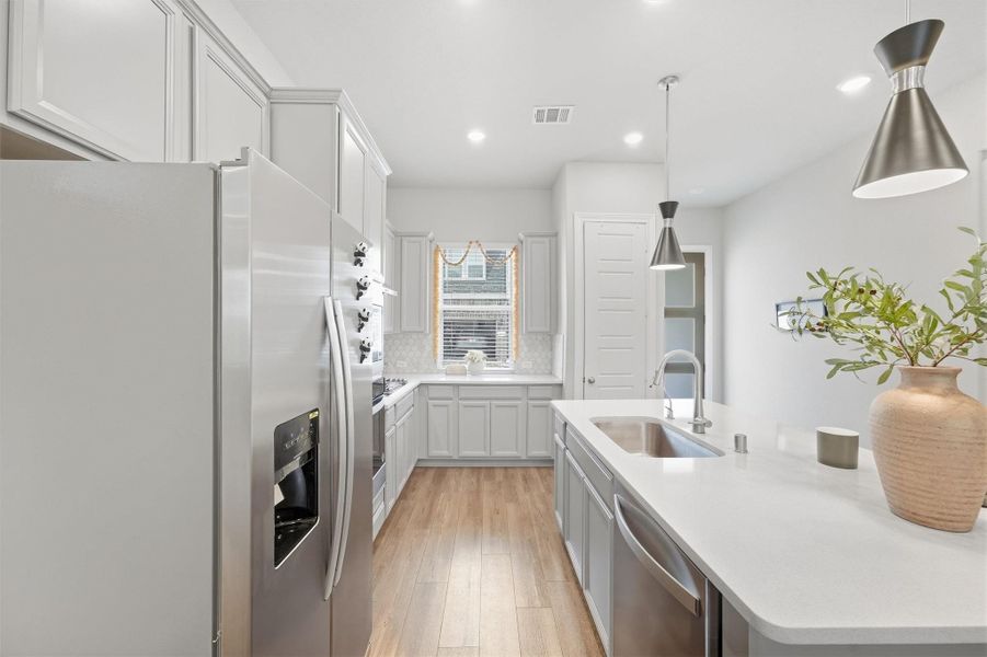 Kitchen centers around a large island, extensive cabinetry, generous counter space, and stainless steel appliances.