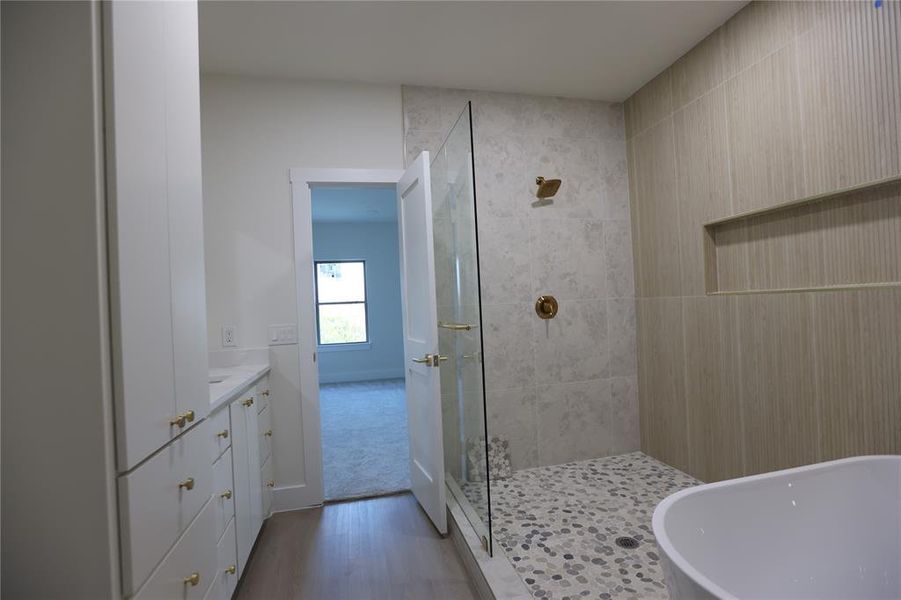 Bathroom with a freestanding bath, a tile shower, vanity, and dark wood finished floors Bathroom with a freestanding bath, a tile shower, vanity, and dark wood finished floors