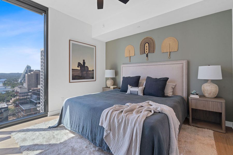 Representative Photo. Primary Bedroom with wood flooring, large window, ceiling fan, and window treatments included
