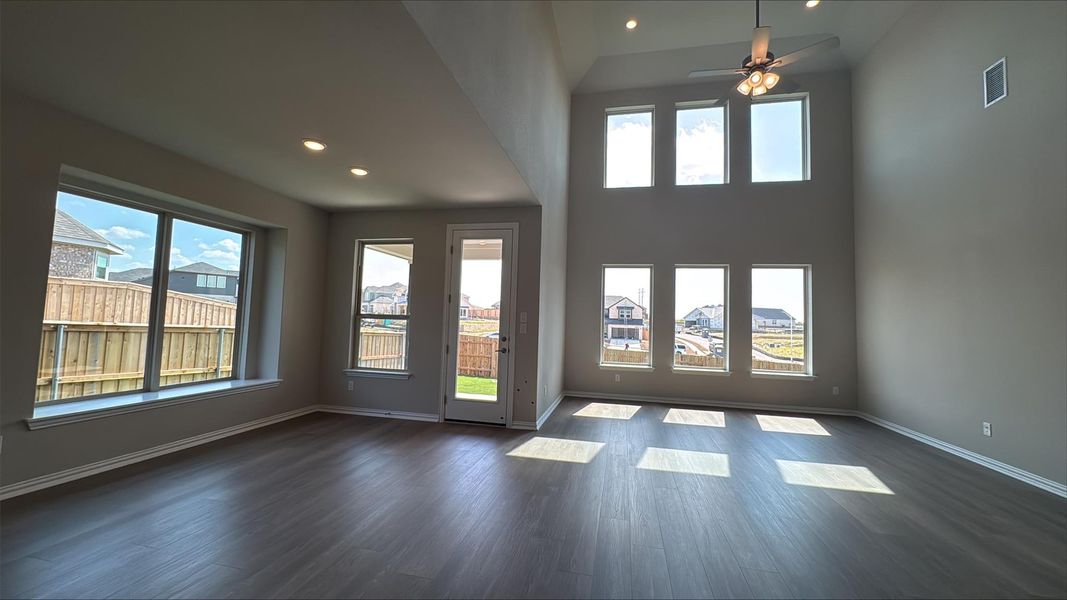 Unfurnished living room with recessed lighting, dark wood-style flooring, ceiling fan, and a towering ceiling