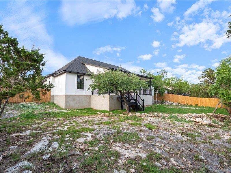 The property features an exterior with white siding and a dark roof, complemented by a wooden fence