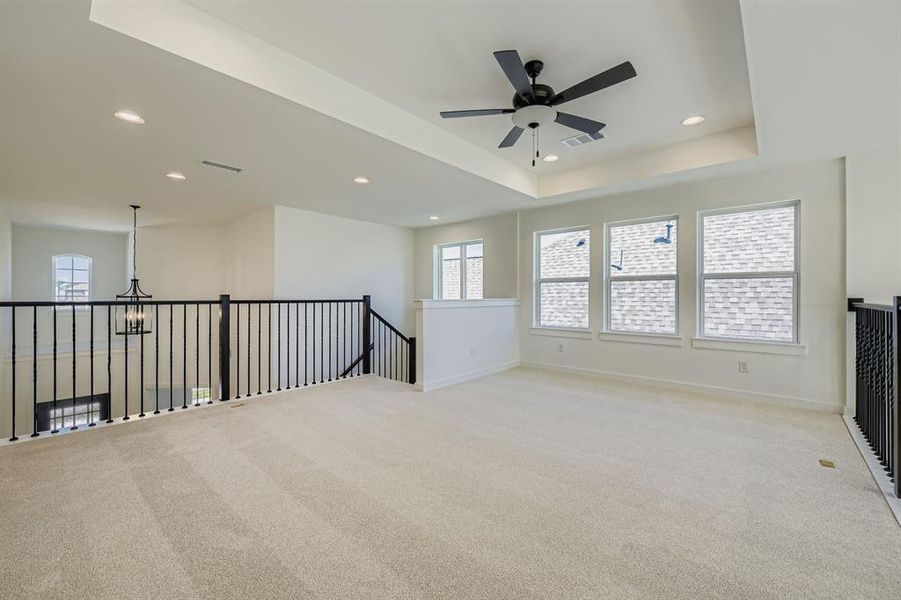 Empty room with healthy amount of natural light, light carpet, a ceiling fan, recessed lighting, and a raised ceiling Empty room with healthy amount of natural light, light carpet, a ceiling fan, recessed lighting, and a raised ceiling