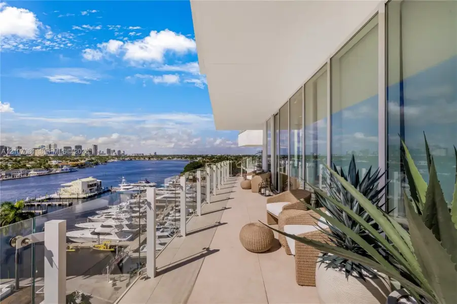 Expansive covered balcony featuring glass railing, smooth concrete flooring, and floor-to-ceiling windows Expansive covered balcony featuring glass railing, smooth concrete flooring, and floor-to-ceiling windows