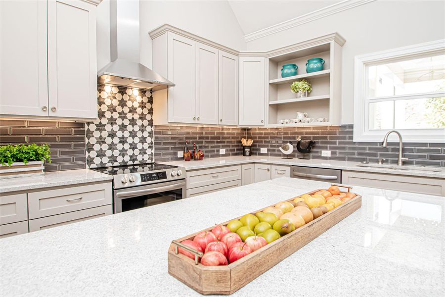 This stunning kitchen with vaulted ceilings showcases stainless steel appliances, granite countertops, a stylish gray subway tile backsplash, and soft-close cabinetry with convenient pull-out drawers.