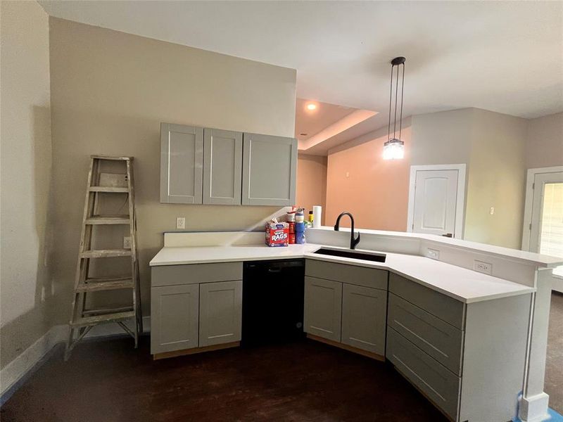 Kitchen featuring gray cabinetry, hanging light fixtures, sink, black dishwasher, and kitchen peninsula