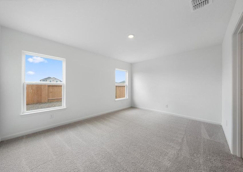 Spacious master bedroom with windows that brighten up the space.