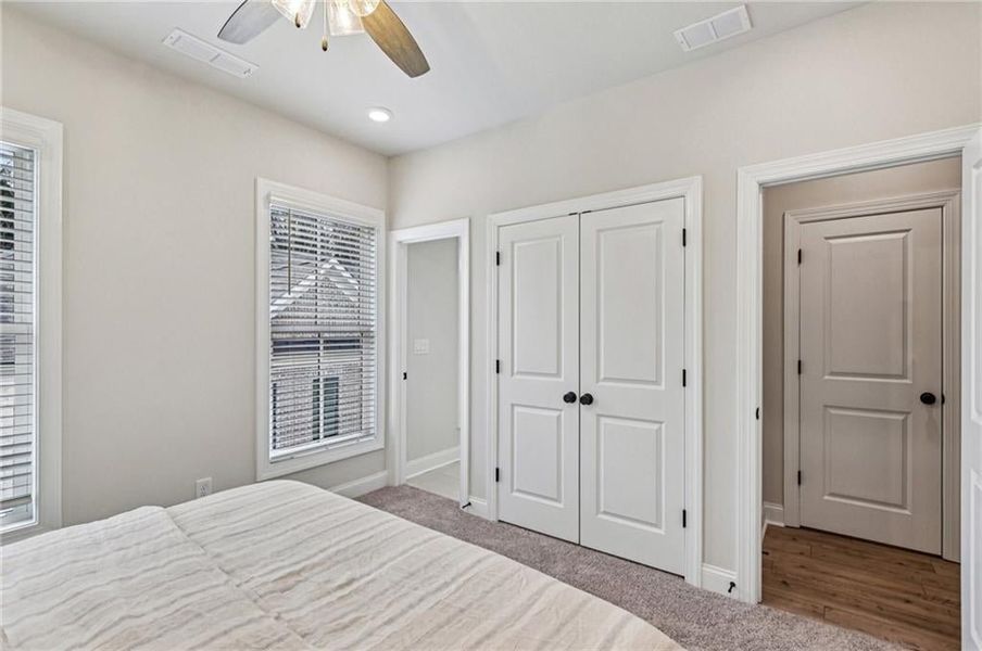 Carpeted bedroom featuring ceiling fan and a closet