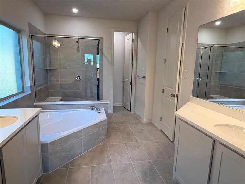 Bathroom with a glass-enclosed shower, built-in shower bench, and a corner soaking tub Bathroom with a glass-enclosed shower, built-in shower bench, and a corner soaking tub