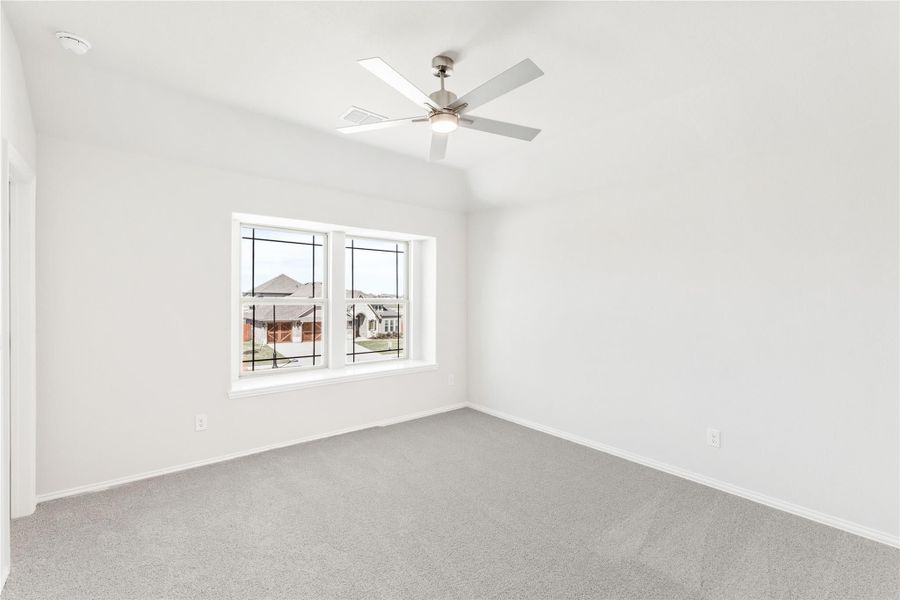 Empty bedroom with gray carpet, ceiling fan, vaulted ceiling, and double window with neighborhood view Empty bedroom with gray carpet, ceiling fan, vaulted ceiling, and double window with neighborhood view