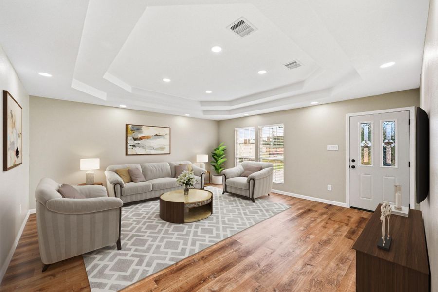 Virtually Staged: This spacious living area offers a bright, open-concept layout with warm wood-look flooring. The elegant tray ceiling with recessed lighting adds architectural detail and creates an airy, upscale feel. Plenty of room for both relaxing and entertaining.