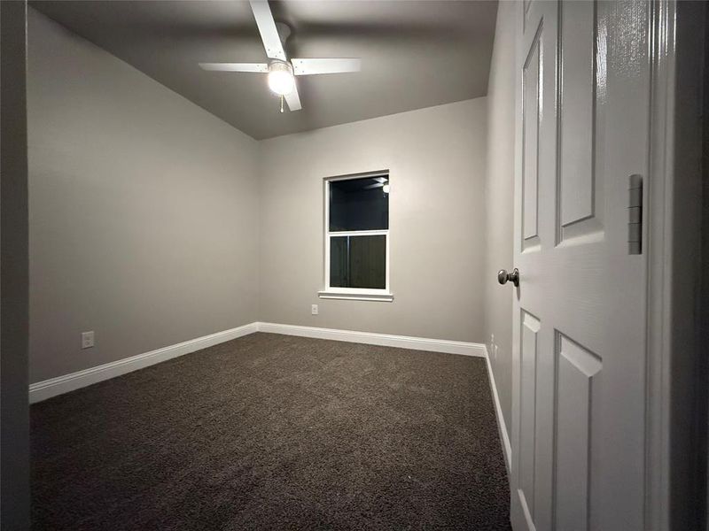 room with dark colored carpet and a ceiling fan
