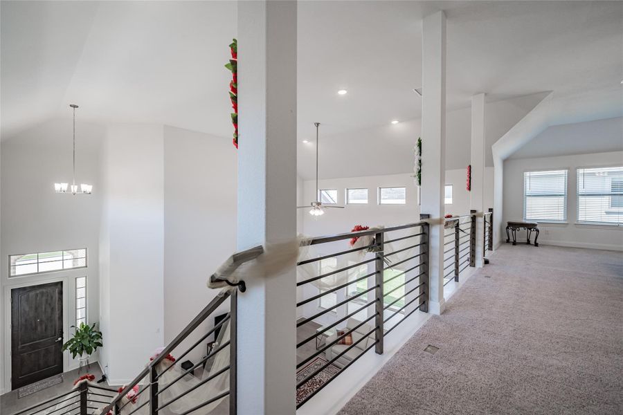 A spacious landing connects bedrooms, offering an elegant view of the grand entryway below.