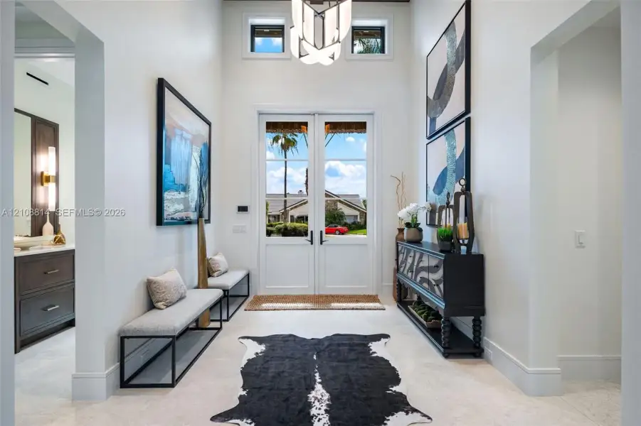 Double-entry glass paneled doors, high ceilings, geometric chandelier, clerestory windows, and light-toned tile flooring Double-entry glass paneled doors, high ceilings, geometric chandelier, clerestory windows, and light-toned tile flooring