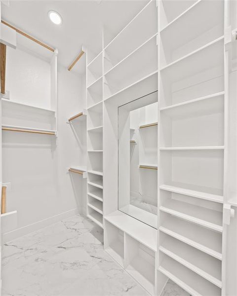 Walk in closet featuring light marble finish floors Walk in closet featuring light marble finish floors