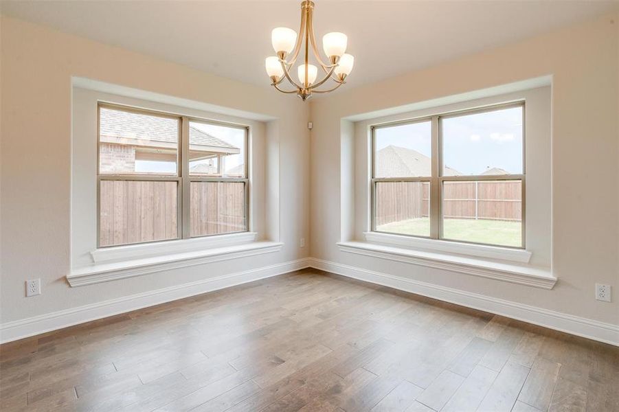 Spare room featuring a notable chandelier and hardwood / wood-style flooring