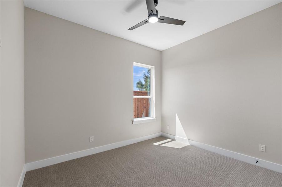 Carpeted spare room featuring ceiling fan