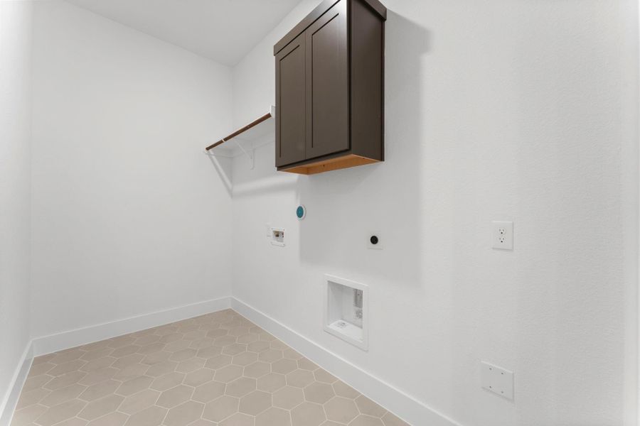 Utility room with overhead storage cabinetry, hanging space, and tile flooring. Utility room with overhead storage cabinetry, hanging space, and tile flooring.