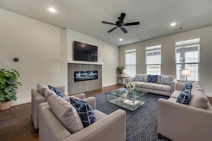 Living area featuring visible vents, baseboards, ceiling fan, a fireplace, and wood finished floors