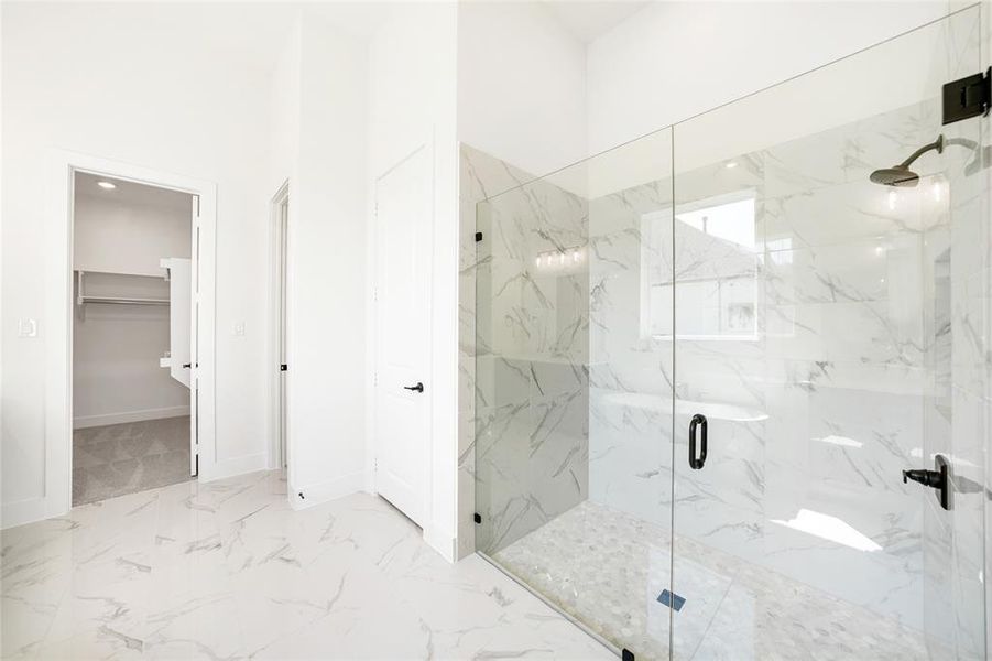 Bathroom with a marble finish shower, a spacious closet, light marble finish flooring, and recessed lighting