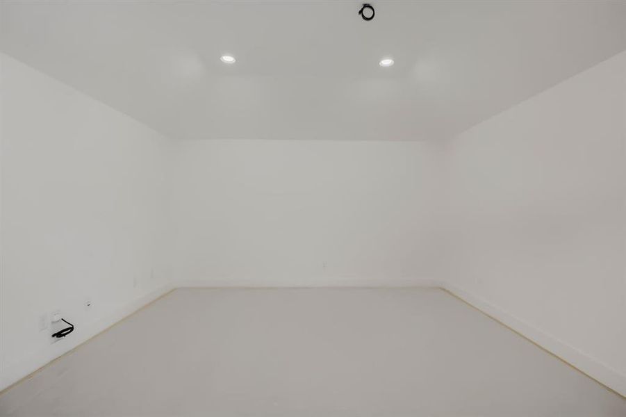 Room featuring white walls, light-toned flooring, recessed ceiling lighting, and a minimalist design Room featuring white walls, light-toned flooring, recessed ceiling lighting, and a minimalist design
