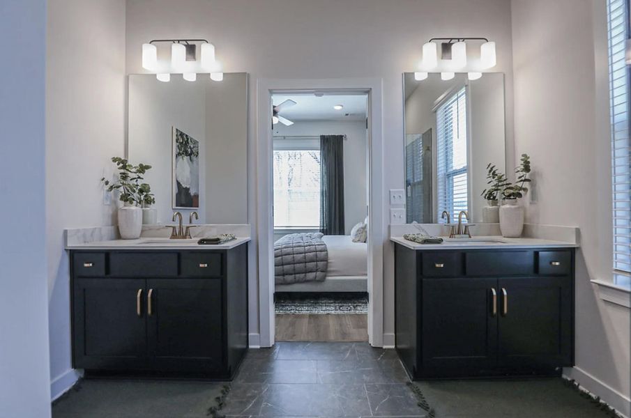 Dual vanity area featuring dark cabinetry with gold-toned hardware, undermount sinks, and light-toned countertops
