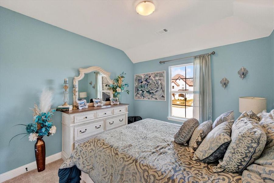 Bedroom featuring light colored carpet and vaulted ceiling Bedroom featuring light colored carpet and vaulted ceiling
