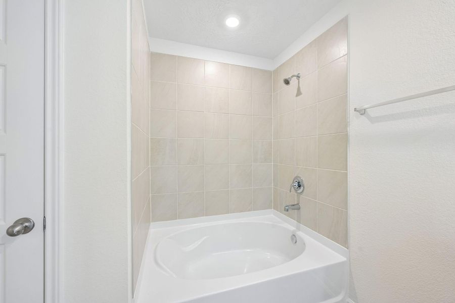This alternate view of the primary bathroom showcases a large tub/shower combination with tile surround and the walk-in closet! This alternate view of the primary bathroom showcases a large tub/shower combination with tile surround and the walk-in closet!