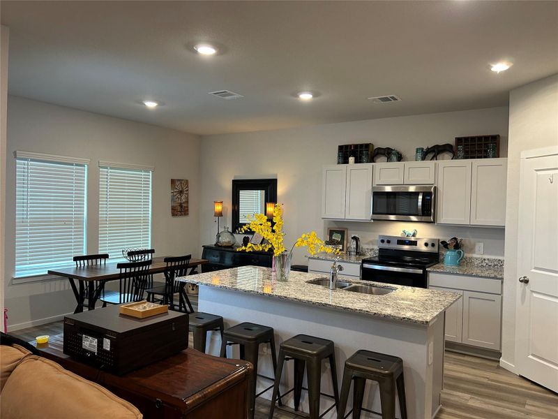 Kitchen and dining area featuring a central island with a double basin sink and granite countertops