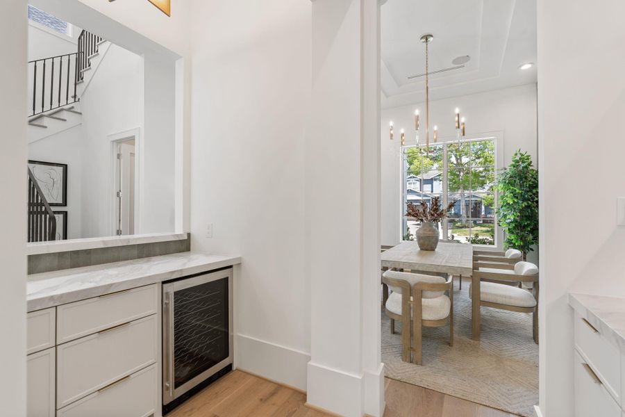 This transition space connects the dining room to the kitchen, featuring additional storage, a built-in beverage fridge, and clean architectural lines that enhance flow and usability.