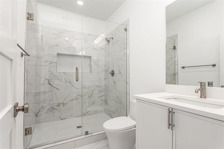 Bathroom featuring marble finish flooring, vanity, a marble finish shower, toilet, and recessed lighting