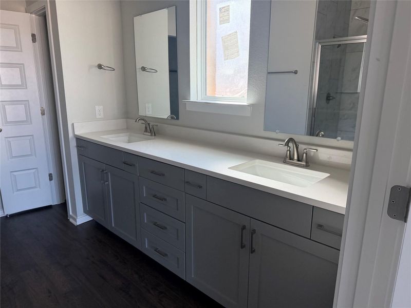 Clean lines and a double vanity define this contemporary restroom space with dark plank flooring.