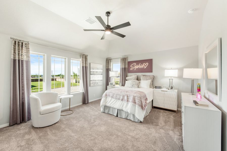 Bedroom with carpet flooring, ceiling fan, large windows, and white dresser with accent chair seating area