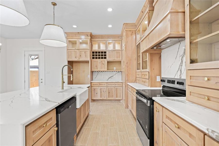 Kitchen with light wood finish cabinetry, stainless steel appliances, and light stone counters Kitchen with light wood finish cabinetry, stainless steel appliances, and light stone counters