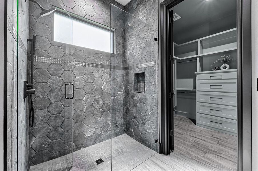 Full bathroom with a shower stall, wood finished floors, and a spacious closet Full bathroom with a shower stall, wood finished floors, and a spacious closet