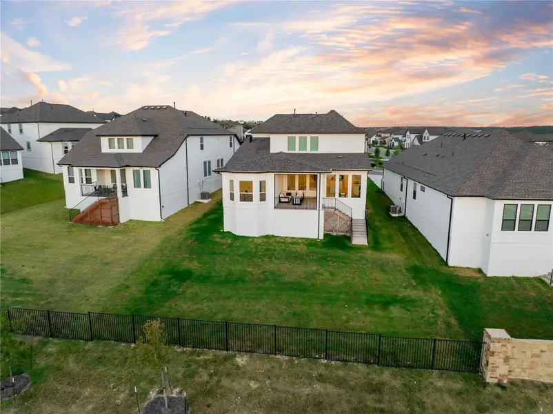 Back of property at dusk featuring a patio, a residential view, a shingled roof, and stucco siding