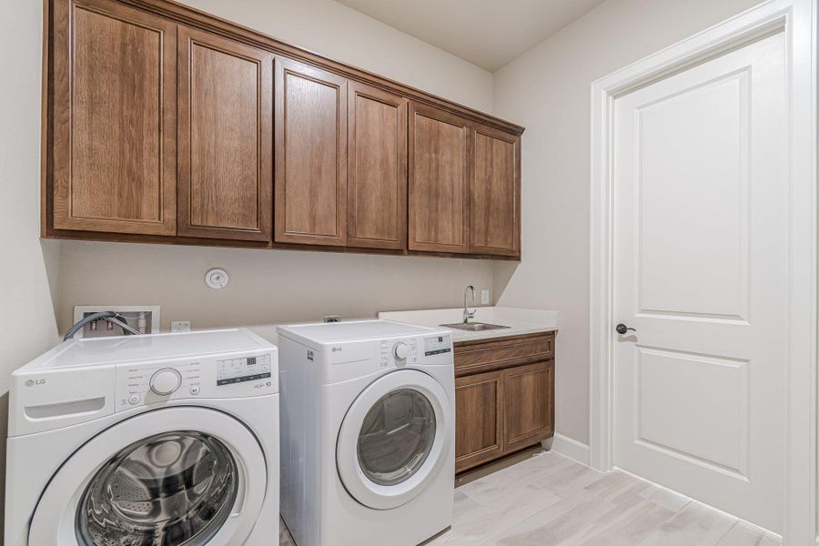 Laundry area with cabinet space, separate washer and dryer, and a sink