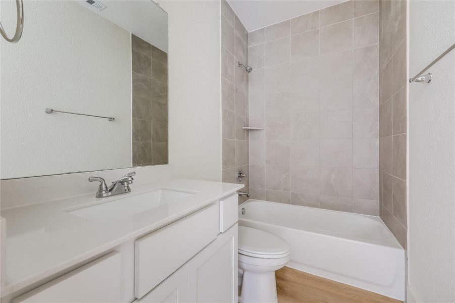 Bathroom with tub / shower combination, vanity, and light wood finished floors Bathroom with tub / shower combination, vanity, and light wood finished floors