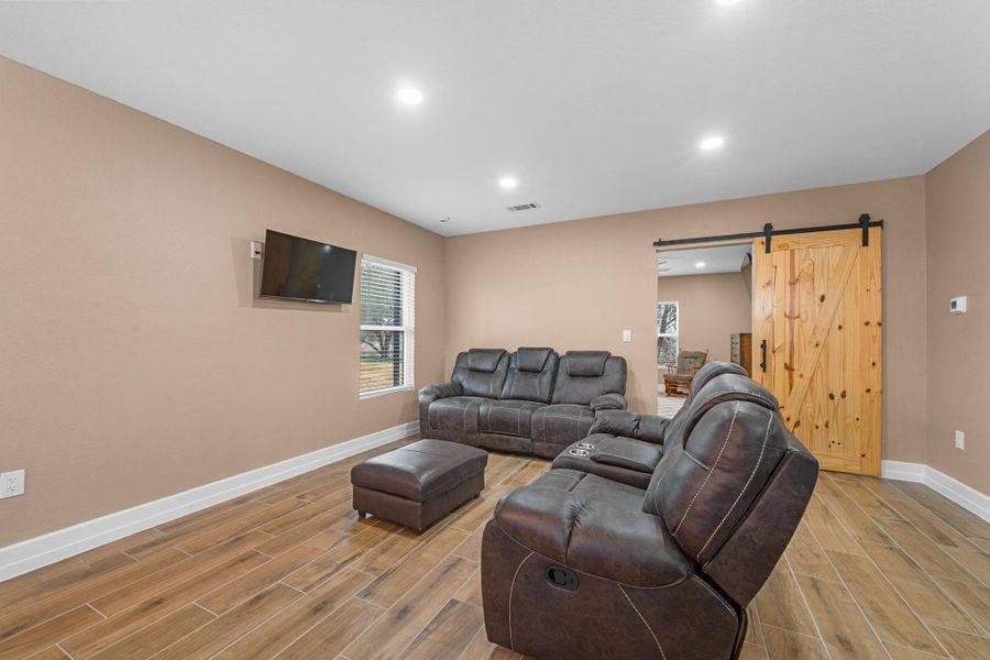 A stunning natural wood sliding barn door with matte black hardware serves as a functional piece of art.