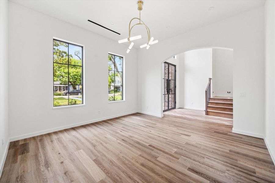 Alternate view of formal dining room with large windows facing the (street) front of the home, while an arched doorway leads to the entry foyer.