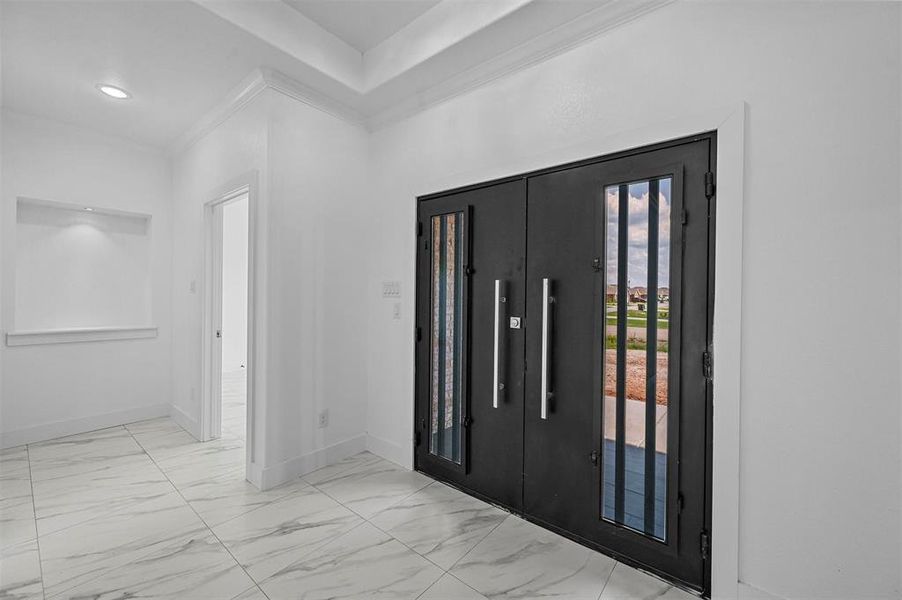 Foyer entrance with light tile patterned flooring and ornamental molding