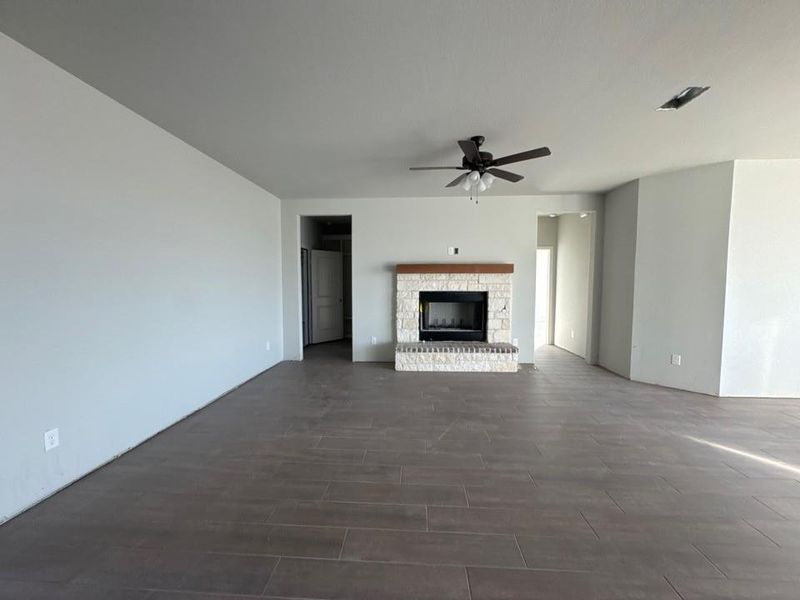 Unfurnished living room featuring a fireplace, wood finish floors, and ceiling fan