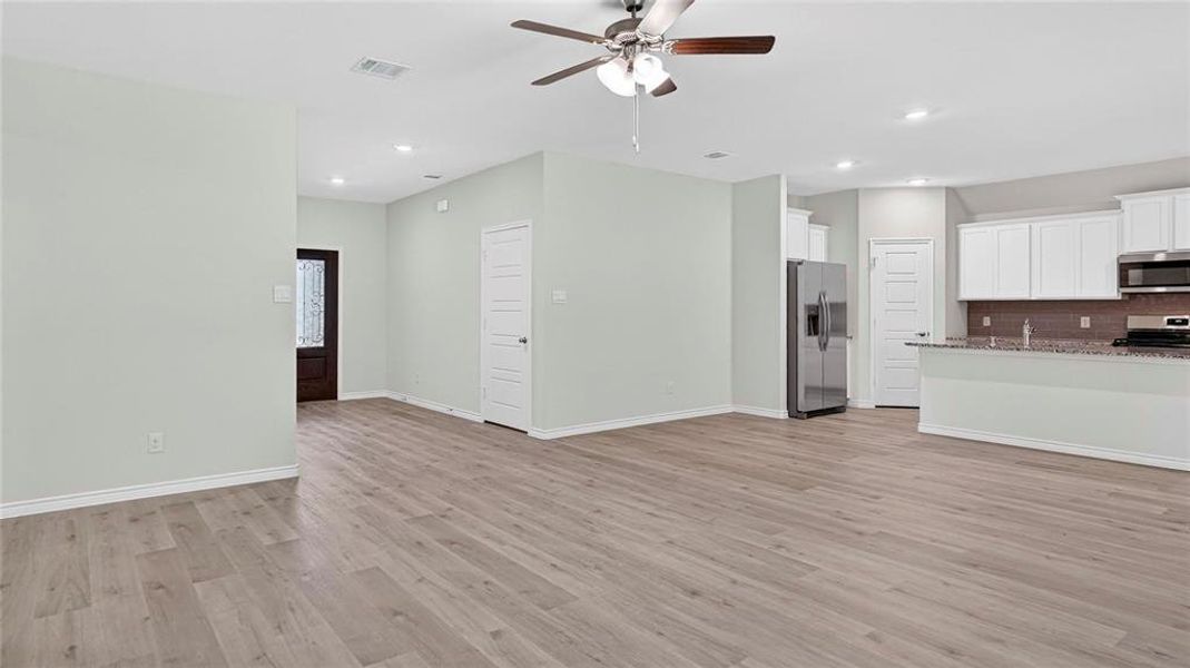 Open-concept living area with wood-finish flooring, recessed lighting, and a ceiling fan