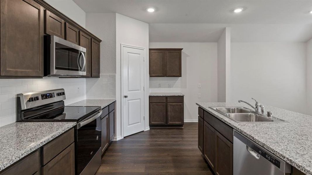 Kitchen with stainless steel appliances, dark wood-style floors, dark wood finish cabinetry, backsplash, and recessed lighting